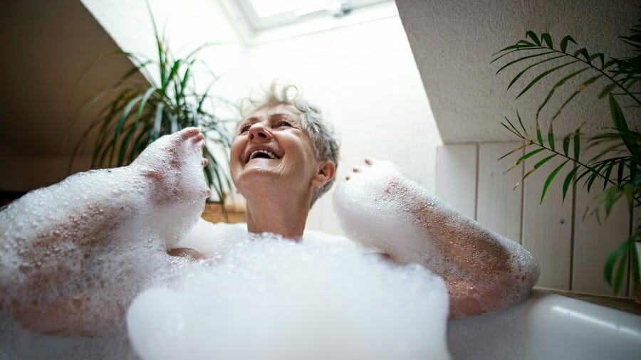 Cheerful senior woman washing in a bubble bath